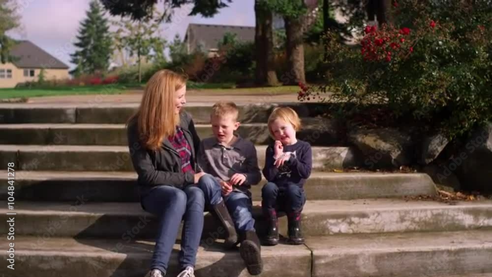 A mother and two kids posing on steps outside for pictures and being silly, slow motion A mother and two kids posing on steps outside for pictures and being silly, slow motion