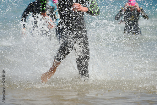 Triathletes running out of the water on triathlon race.