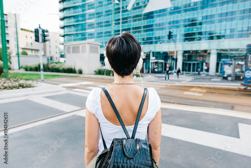 Half length rear view of a caucasian woman with backpack listeni photo