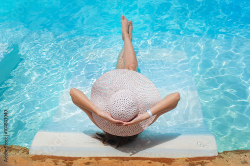 legs and a hat of woman in the pool water