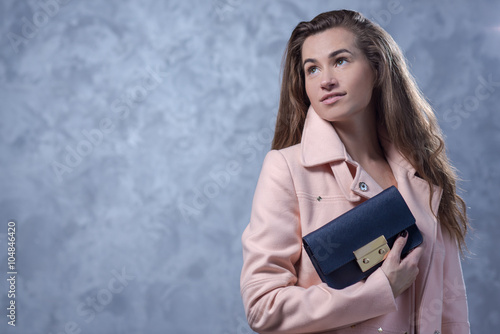 Positive emotional portrait of young and pretty girl with stylish bag