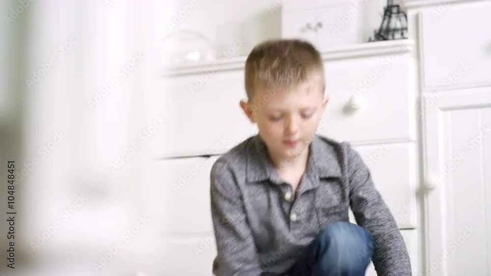 Little boy sitting on the floor at home reading an origami book and folding origami Little boy sitting on the floor at home reading an origami book and folding origami