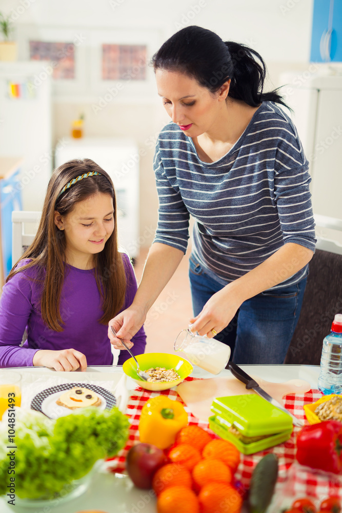Mother making breakfast for her children in the morning and a sn Mother making breakfast for her children in the morning and a sn