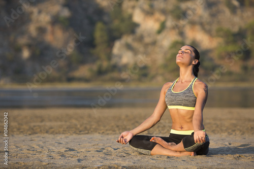 Woman doing yoga on sand