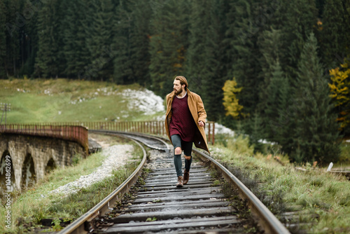 brutal bearded man walks on the tracks