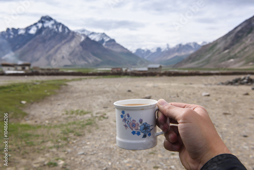 Hand holding coffee cup with Himalaya Mountain