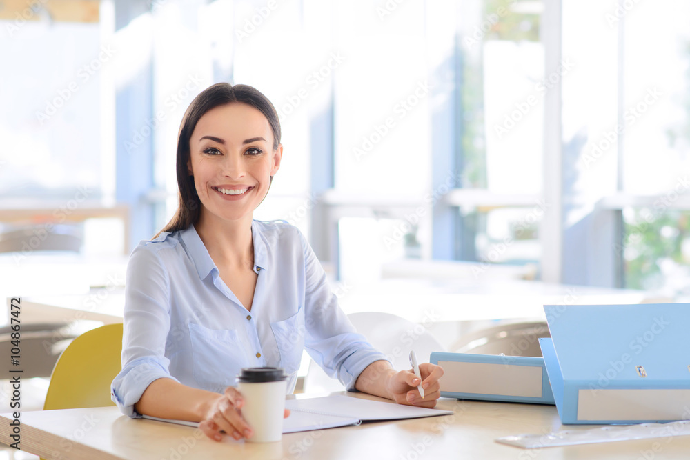 Positive businesswoman sitting at the table Positive businesswoman sitting at the table