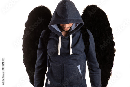 young man in gray jacket with his head in the hood standing with her hands on her back and black wings