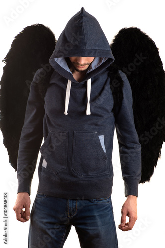 young man in gray jacket with hood thrown over his head and jeans standing with her hands on back and black wings