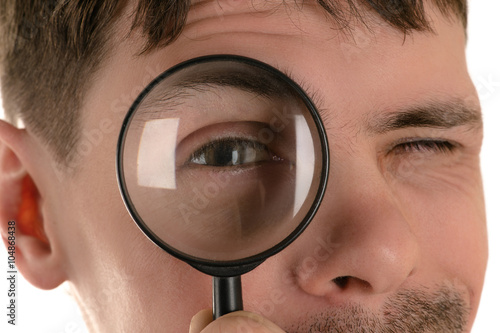 portrait of young man looking through a magnifying glass closeup