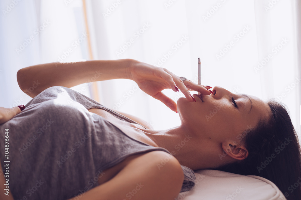 Fototapeta premium Smoking girl lying by the window