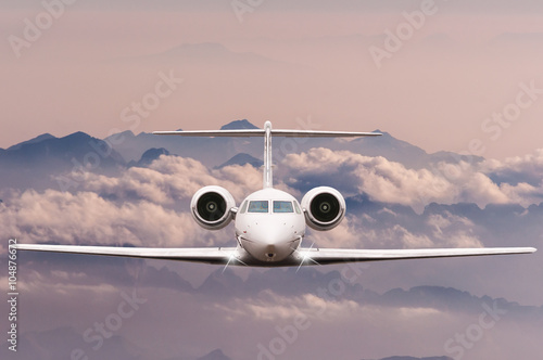 Travel concept. Front view of Jet airliner in flight with sky, cloud and mountain background. Commercial passenger or cargo aircraft, business jet fly over Alps. 