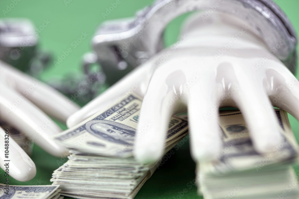 two white ceramic hands with handcuffs on pile of 100 dollar notes two white ceramic hands with handcuffs on pile of 100 dollar notes