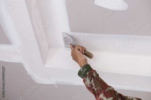 hand of worker using gypsum plaster ceiling joints photo