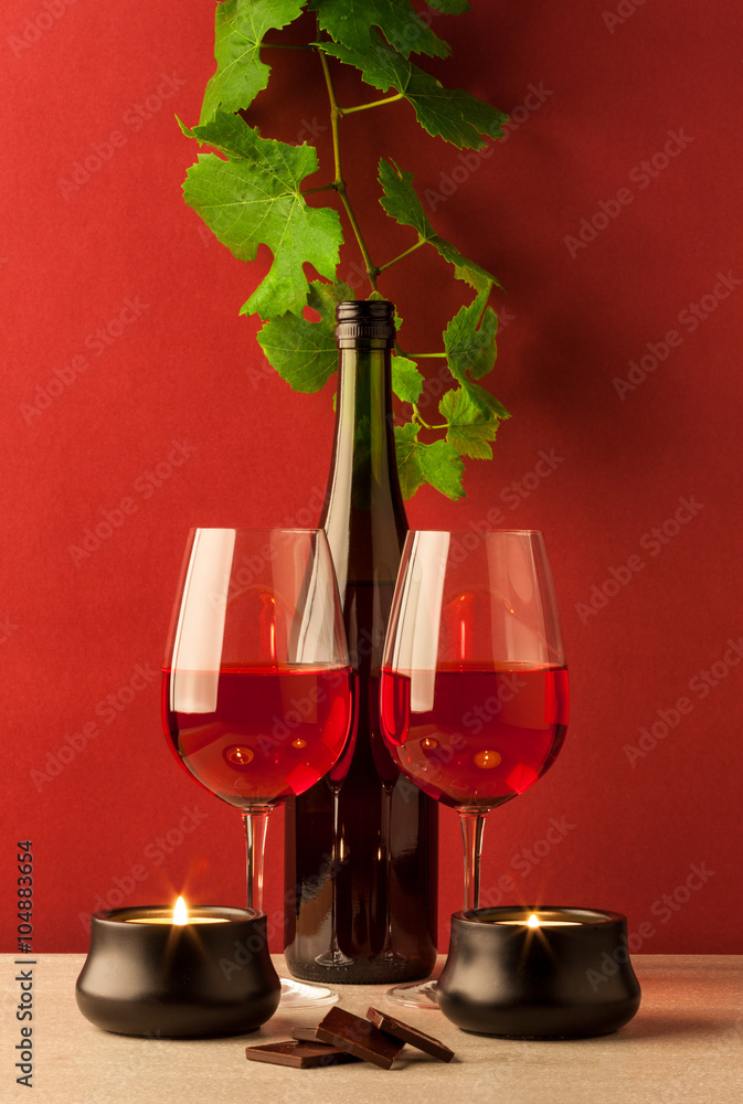 Red wine bottle with two glasses, candles, and chocolate
