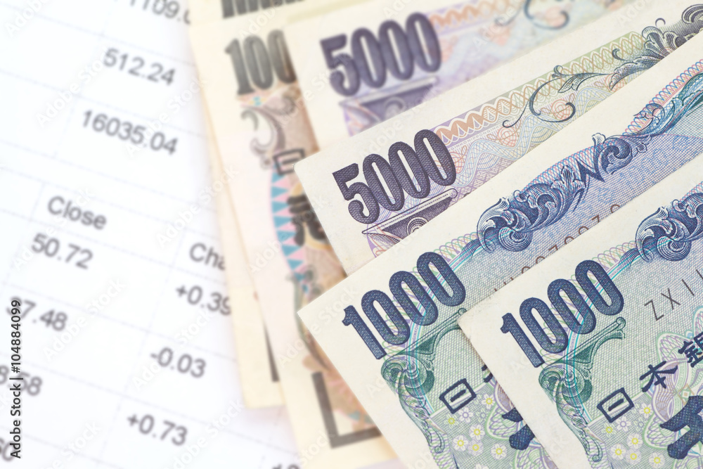 Close - up of Japanese currency yen bank notes and financial chart Close - up of Japanese currency yen bank notes and financial chart
