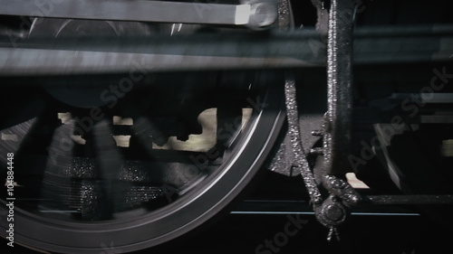 Close-up of steam train wheels moving fast along a track.
