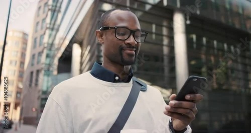 African American businessman walking through city using smart phone
