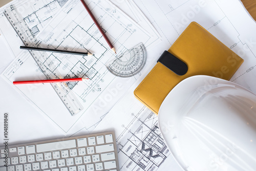 Image of blueprints with level pencil and hard hat on table