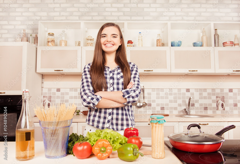 Attractive housewife posing with crossed hands in the kitchen Attractive housewife posing with crossed hands in the kitchen
