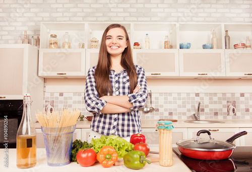 Attractive housewife posing with crossed hands in the kitchen