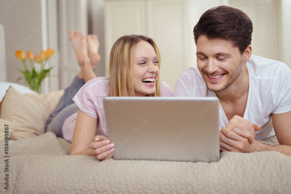 lachendes paar liegt auf dem bett und schaut ein lustiges video am laptop lachendes paar liegt auf dem bett und schaut ein lustiges video am laptop