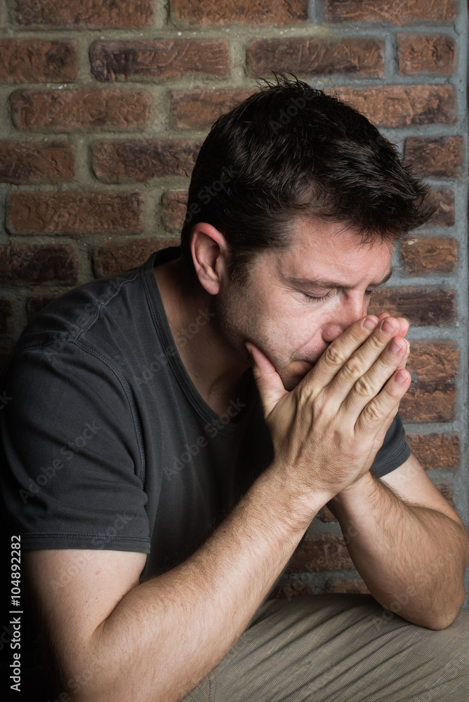 Middle-age man with palms raised to face and eyes closed Middle-age man with palms raised to face and eyes closed
