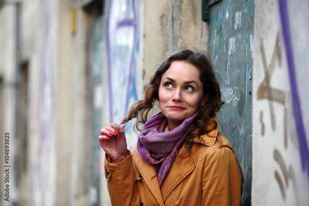 Fototapeta premium Beautiful brunette woman smiling and playing with her curly hair