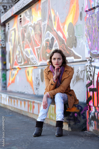 Photography Beautiful brunette woman sitting at a wall with graffiti