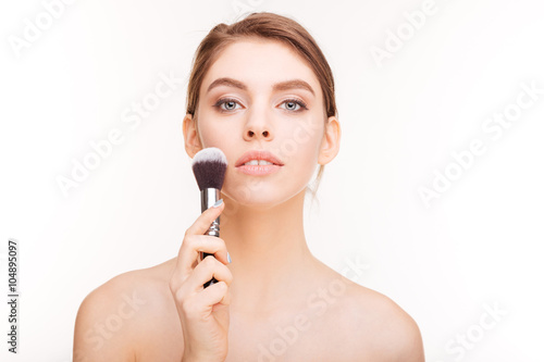 Beauty portrait of sensual charming young woman holding makeup brush
