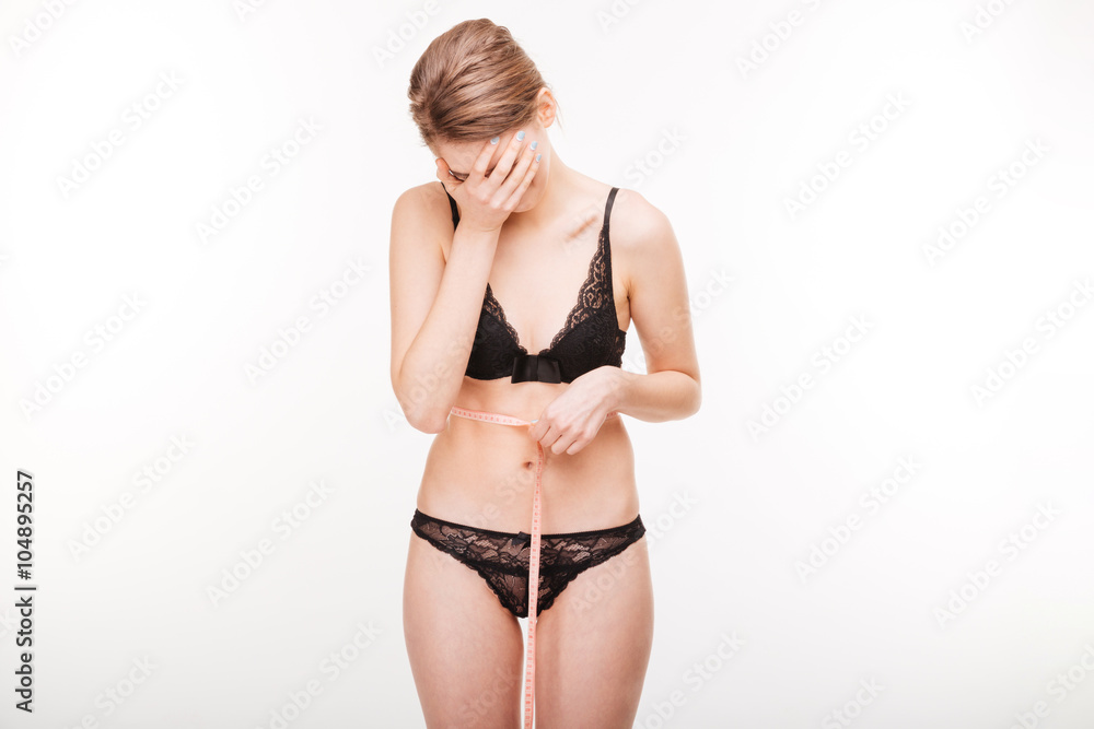 Depressed attractive woman closed face by hand and measuring waist Depressed attractive woman closed face by hand and measuring waist