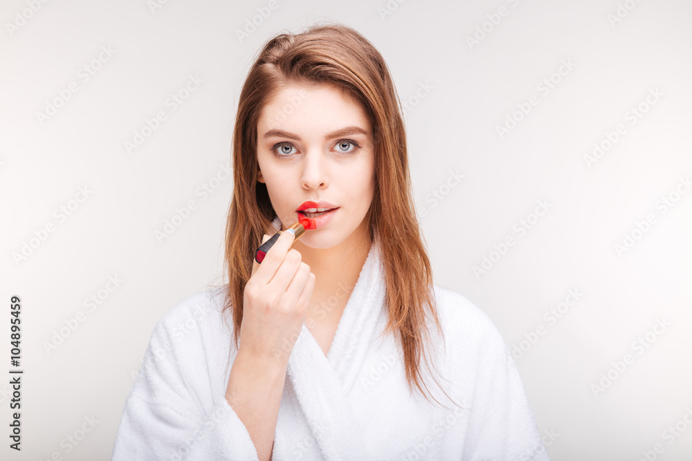 Beautiful sensual woman trying red lipstick on half of lips Beautiful sensual woman trying red lipstick on half of lips