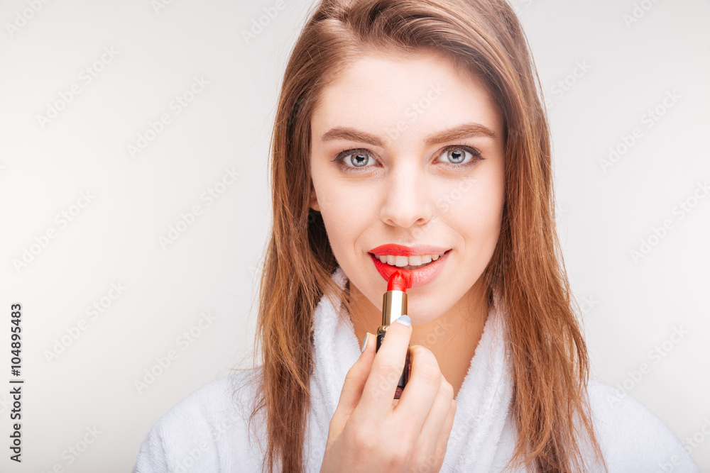 Attractive happy woman applying red lipstick on part of lip Attractive happy woman applying red lipstick on part of lip