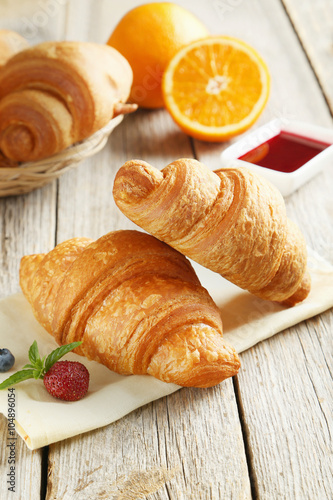 Fresh tasty croissants with berries on grey wooden background
