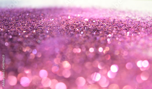 Blurry background of purple glitter sparkles on white surface