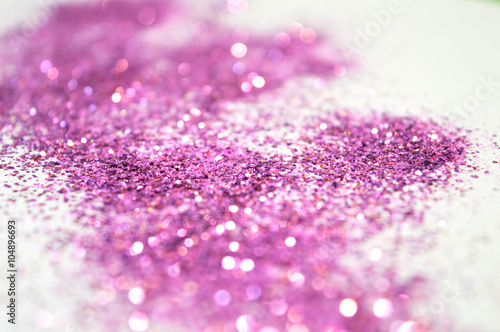 Blurry background of purple glitter sparkles on white surface