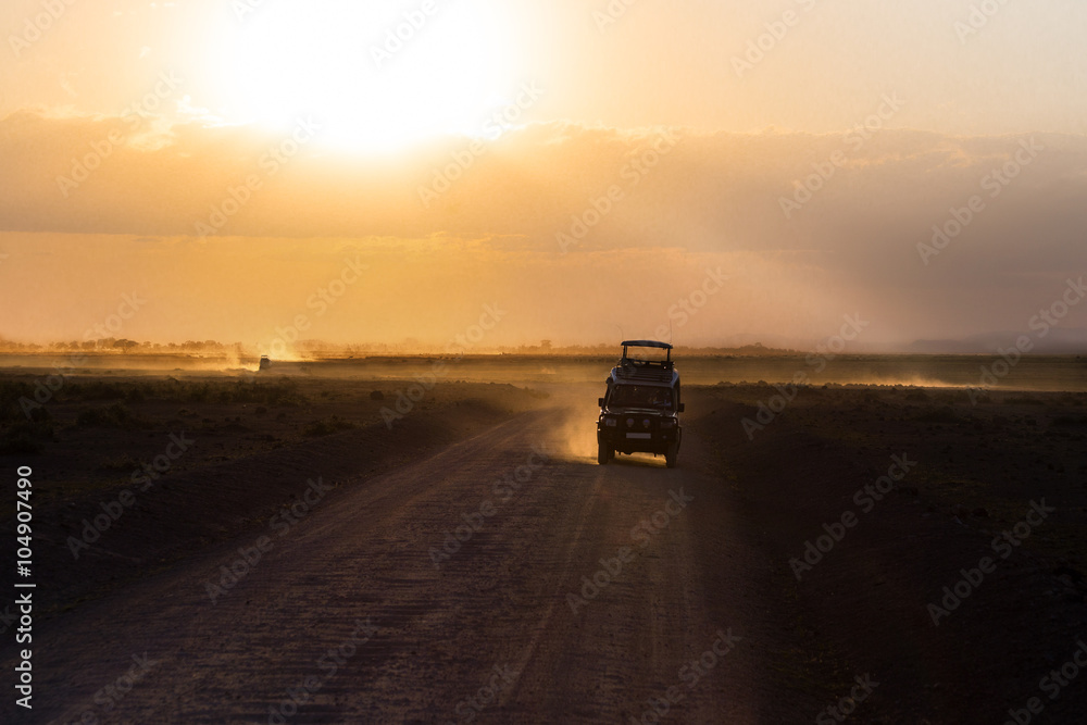 Sunset in african savannah, silhouettes of safari car and animals, Africa, Kenya, Amboseli national park
