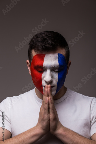 Portrait of Pray France football fan in game  of France national  team with close eyes. UEFA EURO 2016 football fans concept. photo