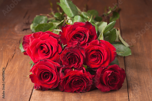 bunch of red roses on wooden table