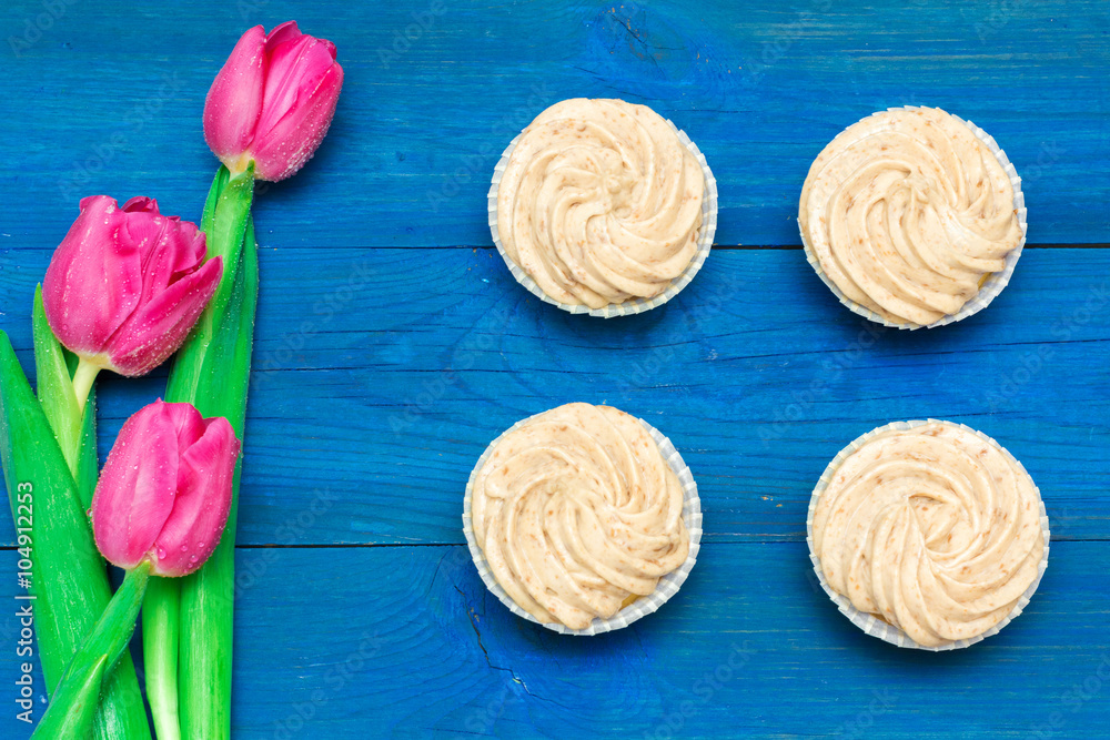 cupcakes with cream and tulips on blue boards cupcakes with cream and tulips on blue boards