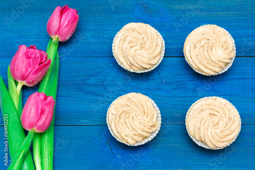 cupcakes with cream and tulips on blue boards