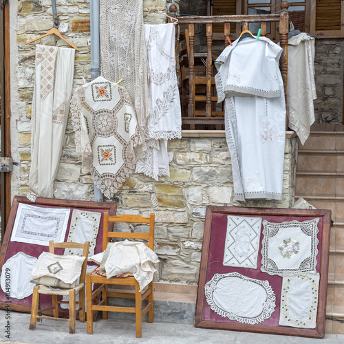 Hand-made laces and needlework hang on shop wall. Pano Lefkara. Cyprus.

