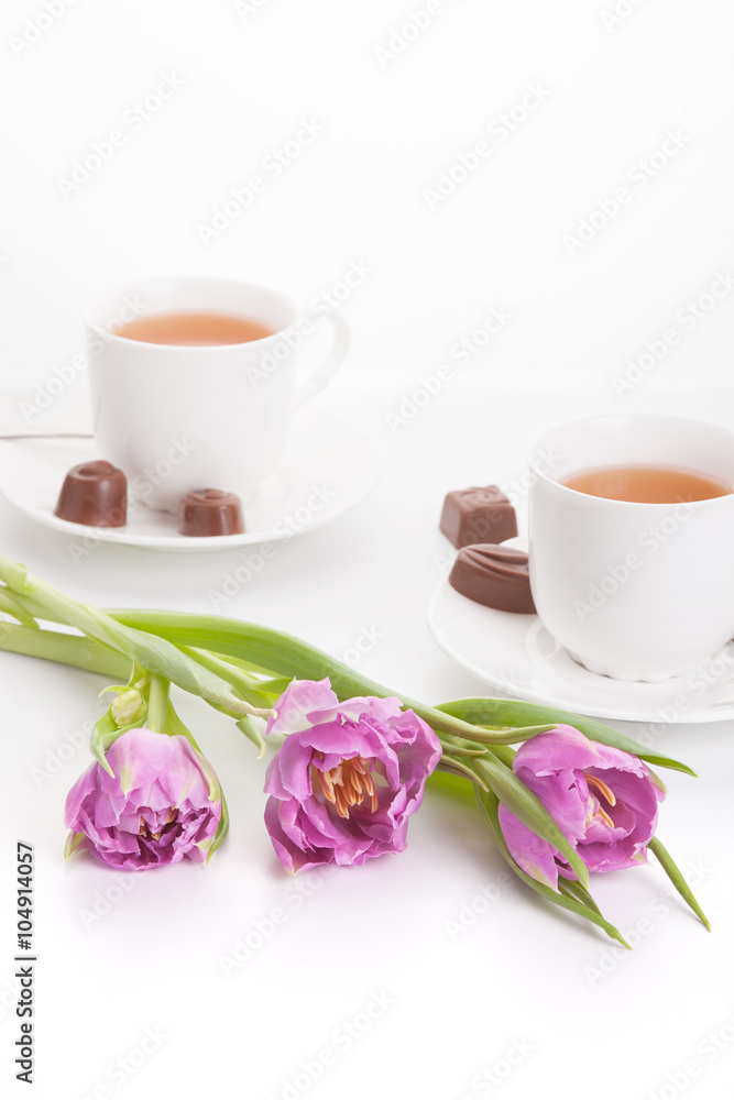 Violet tulips with cups of tea and chocolates Violet tulips with cups of tea and chocolates