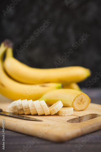 sliced banana with a knife on wooden board