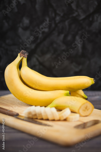 sliced banana with a knife on wooden board