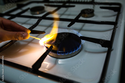 A man lighting the gas stove with a match
