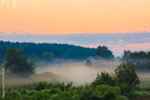 Landscape with sunrise sky, houses in beautiful fog at morning