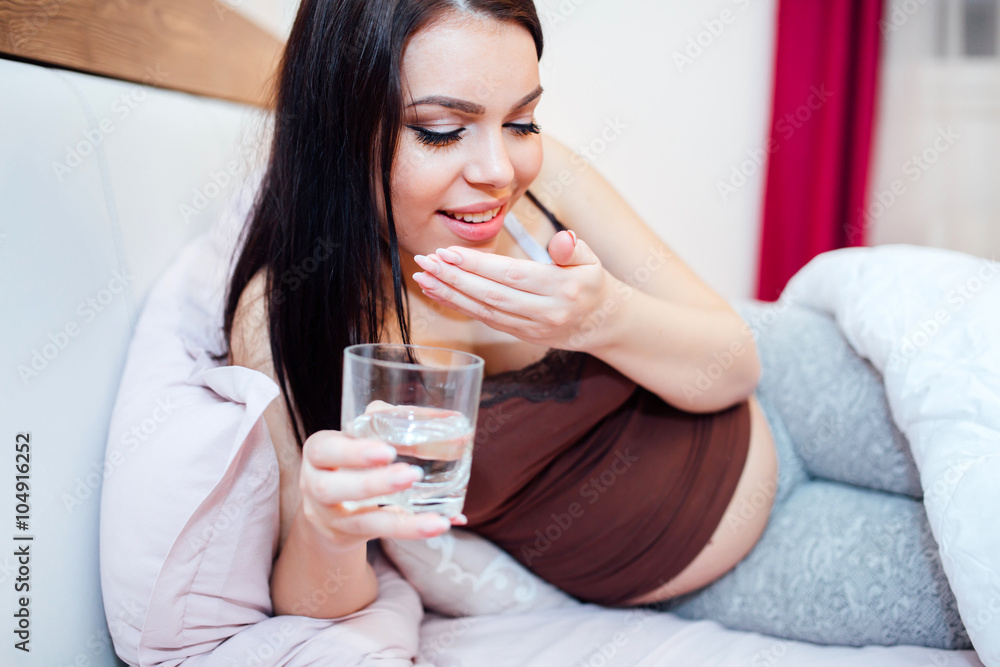 Happy pregnant woman taking supplements