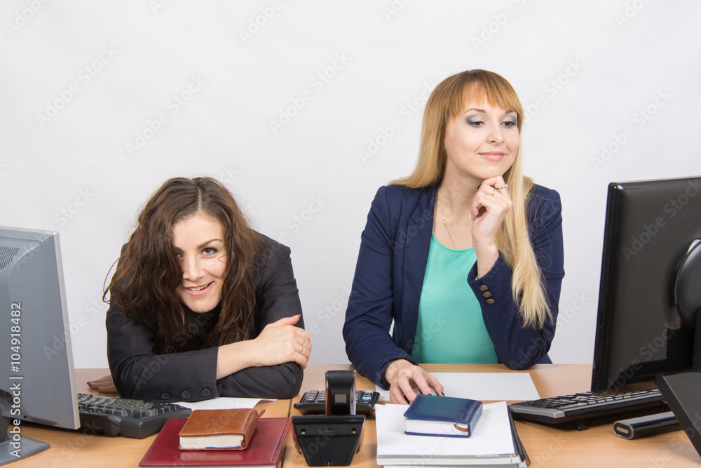 The situation in the office - one girl crazy looks in the picture, her colleague looking at monitor The situation in the office - one girl crazy looks in the picture, her colleague looking at monitor