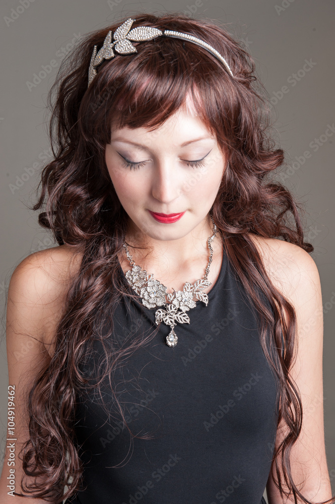 Fototapeta premium Young lady posing with long curled hair and jeweled leaves